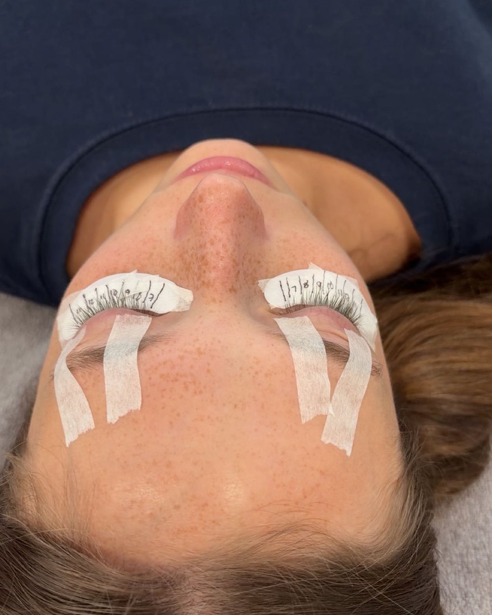 A client relaxing mid-appointment with lash pads on